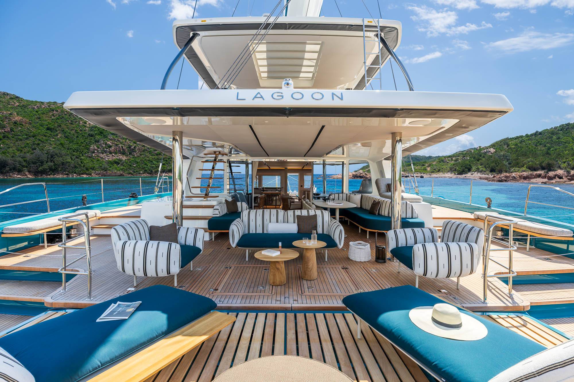 Corporate guests relaxing on the foredeck sunpads of the Lagoon Eigthy2 with a coastal mountain view